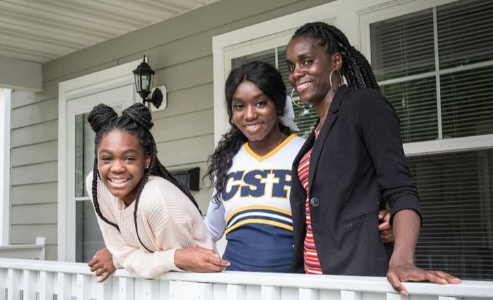 Homeowner and two teen kids smiling on their front porch.