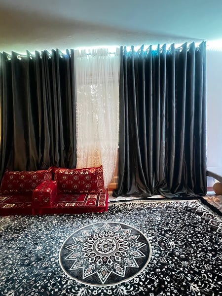 Black curtains with a black and white pattered rug.