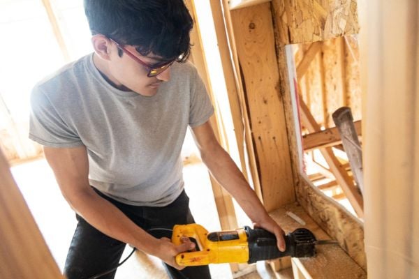 Volunteer drilling the frame of the house.