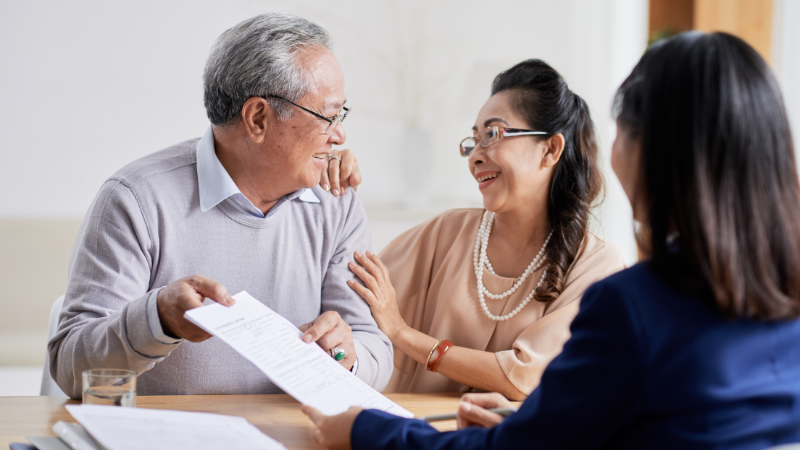 Older couple smiling over papers. 