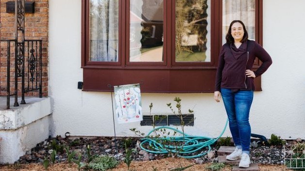 Anne smiling in front of her home.