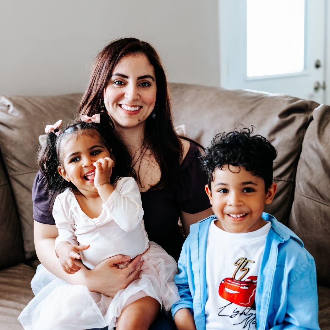 Linda and her kids smiling, sitting on the couch.