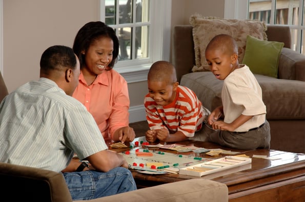 Family of four playing monopoly on a living room table.