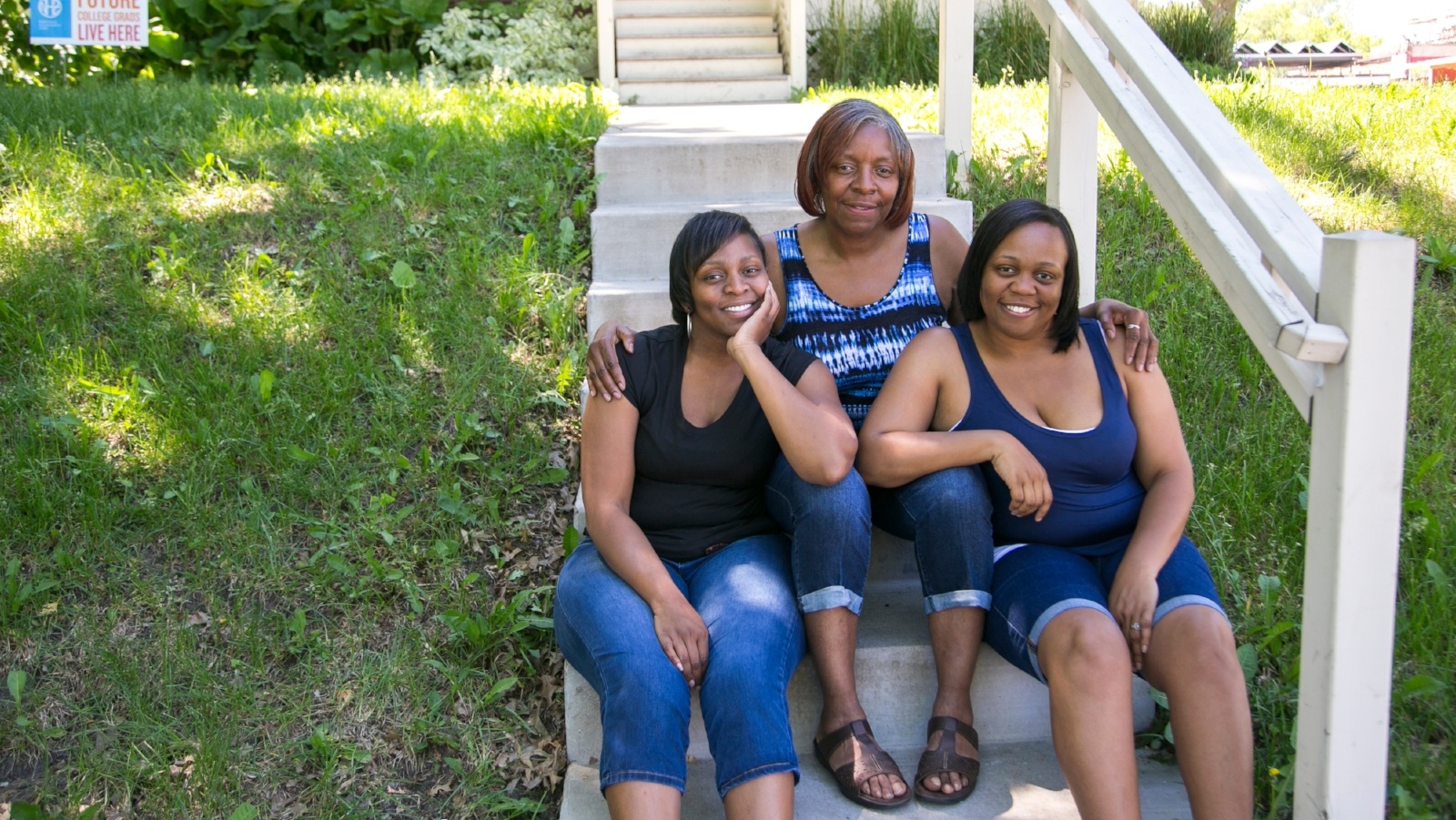 Three women sitting on the front steps of a home
