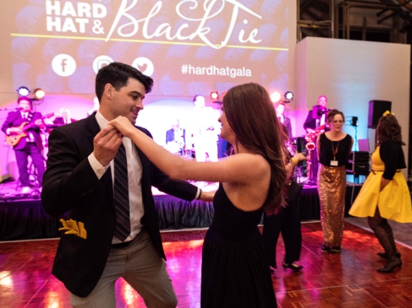 A couple dancing on the dancefloor with a live band in the background.