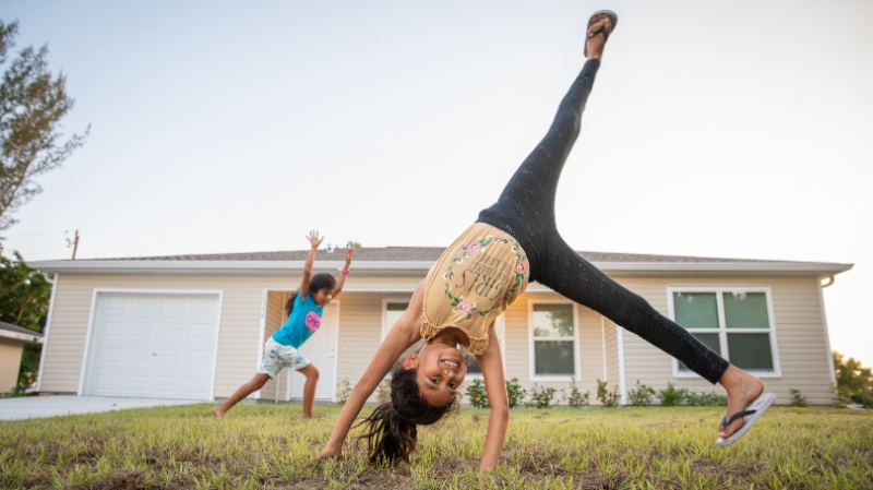 Girl doing a cart wheel in front of her house.