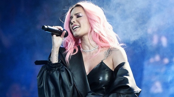 Singer Halsey performing in a black outfit with pink hair.