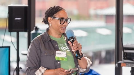 Shereese speaking in to a microphone at a Habitat event.