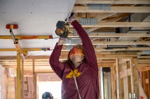 Volunteer use a power tool on the ceiling of a house