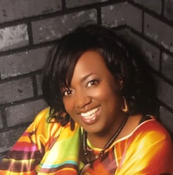 Headshot of Kim Smith-Moore in a yellow and orange shirt.