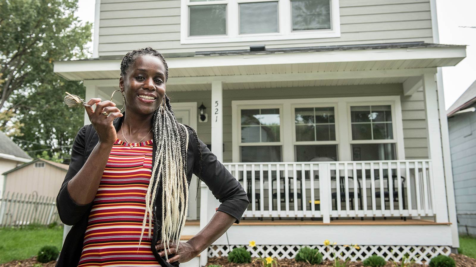LeAndra smiling in front of her house with keys in hand.