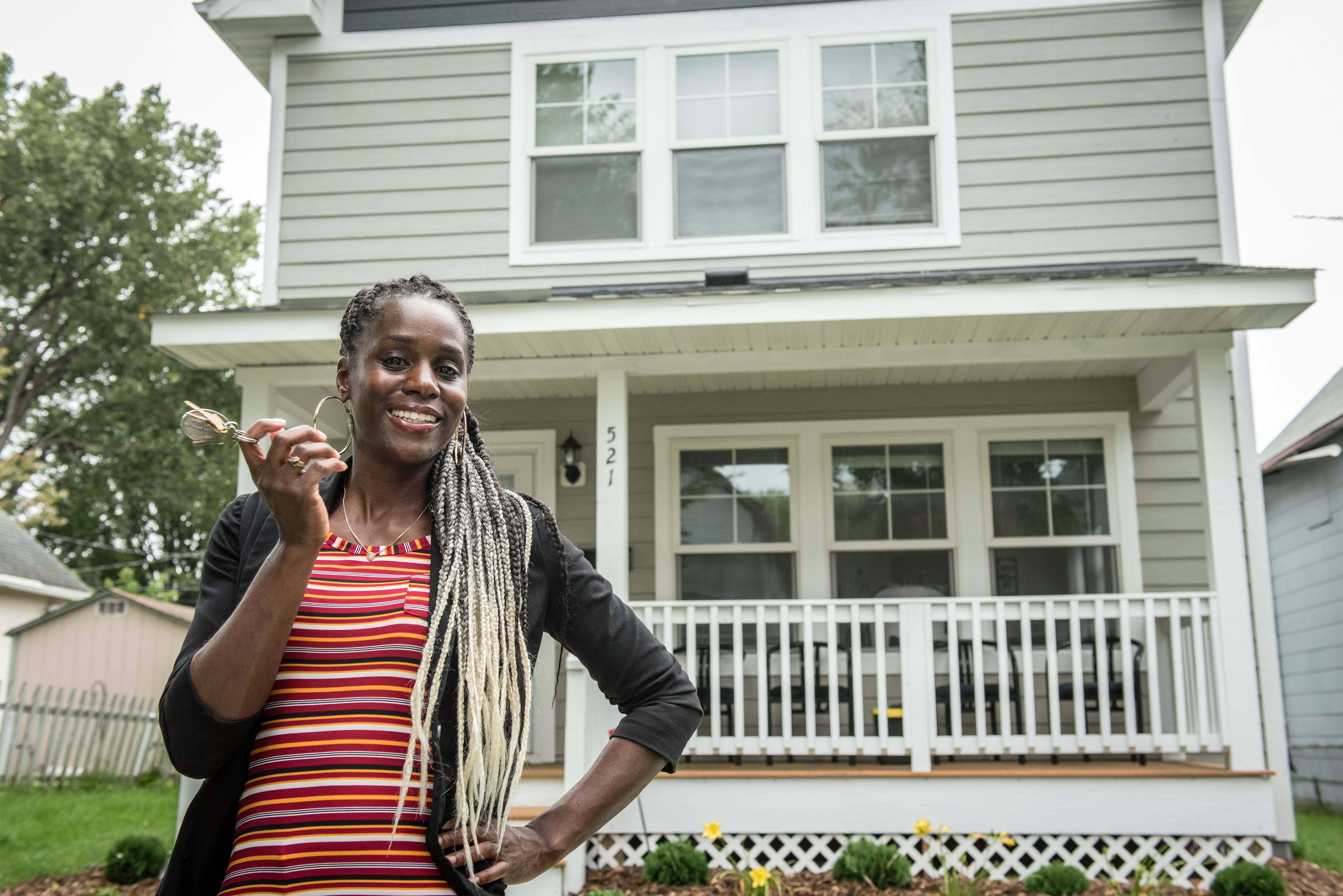 Photo of one of our Habitat Homeowners Homeowner Leandra posing and smiling in front of her home