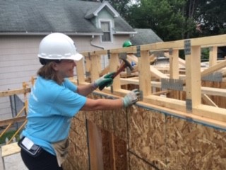 Linda King hammering part of a wall into place.