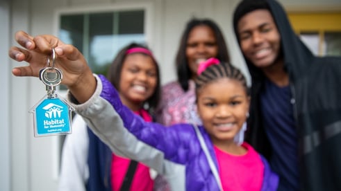 Black family in front of a home and litter girl holding up the house keys.