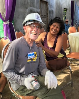 Orin in a hard hat smiling with a Cambodian woman.