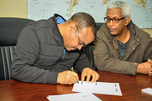 Two people signing forms.