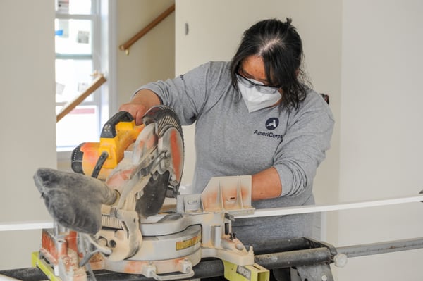 AmeriCorps Member using a table saw to cut trim