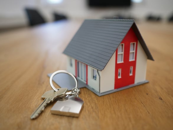 House key and keychain on a table next to a miniature house