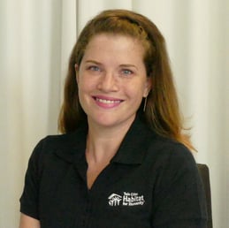 Robyn Bipes-Timm in front of a white background, smiling, wearing a black Habitat polo shirt.