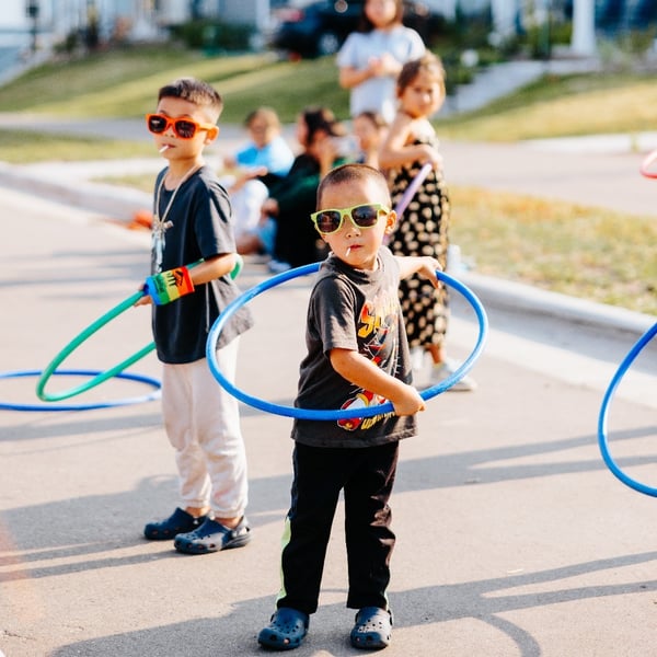 Two kids with sunglasses and hula hoops.