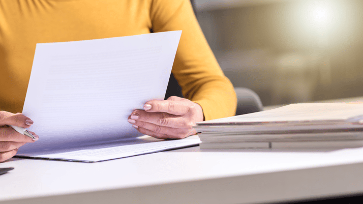 A person holding papers; close-up shot of the papers and hands.