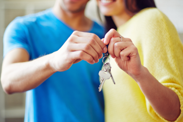 a couple holding a set of keys, zoomed in on their hands