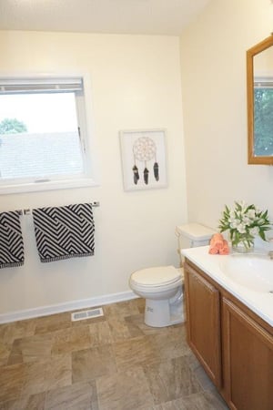 A bathroom with window and tile floor.