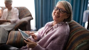 A woman on a living room couch with a tablet.