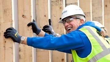 A volunteer smiling and helping raise a wall.