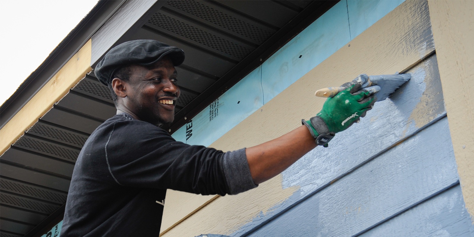 A man painting the side of a house