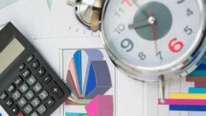 A calculator and alarm clock on papers covered in graphs.