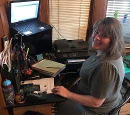 Juanita at home, sitting at her home office desk.