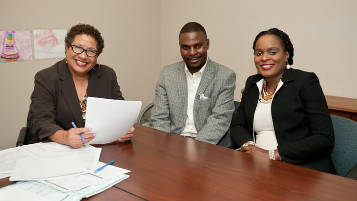 Linda, Financial Coach at Model Cities, smiles with Fred and Brigitte at a coaching session.