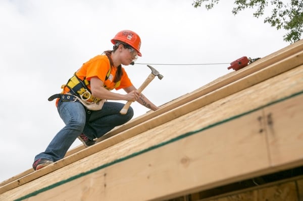 A woman from Andersen's Women Build team hammering on the roof