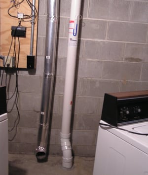 A radon mitigation system with PVC pipe in the basement of a home.
