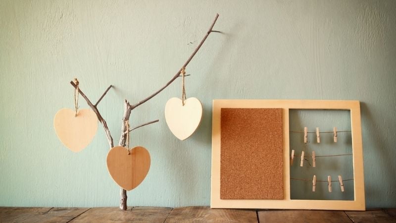 A tree branch with wooden hearts, and a small corkboard with picture hangers.