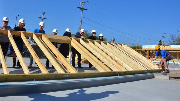 A team of volunteers raising the frame of a wall.