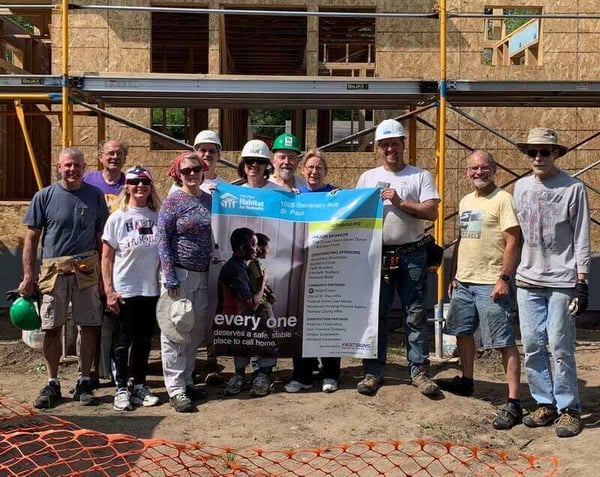 A group of volunteers holding the site sign for the home they're building.