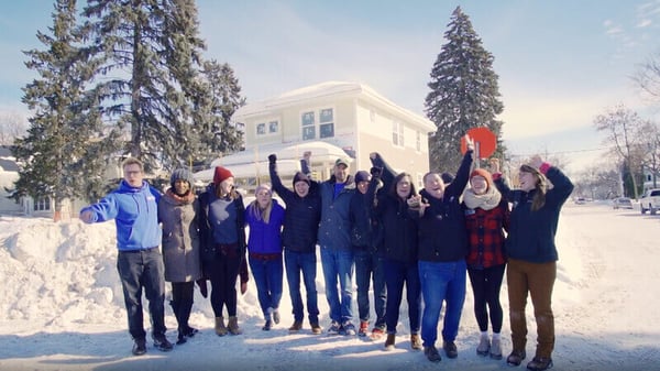 Volunteers celebrating outside a home build site in the snow.