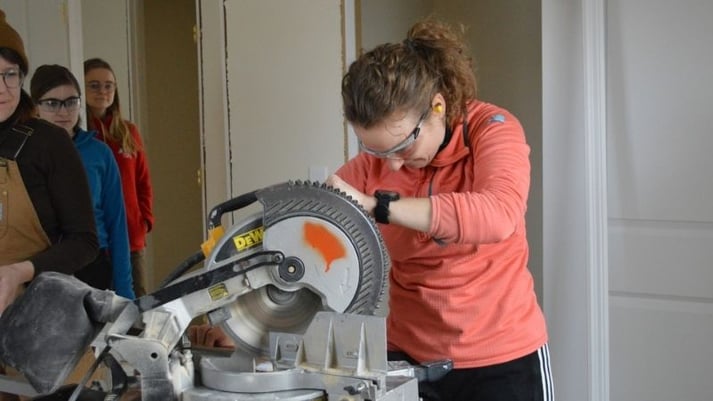 AmeriCorps member using a power saw.