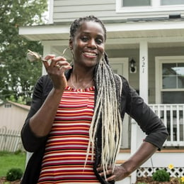 LeAndra holding the keys to her Habitat home, standing on the front lawn of the house.