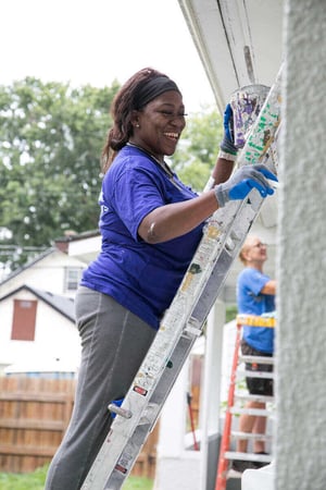 A volunteer painting a house.