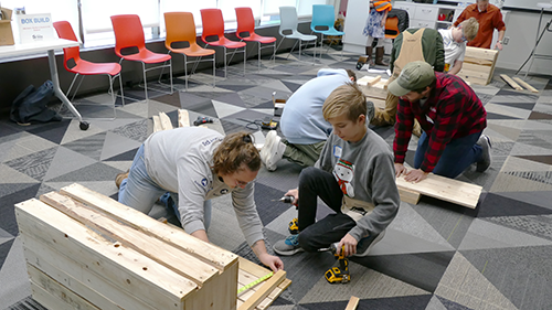 Several people constructing toy boxes at family volunteer day