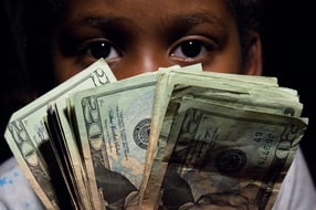 Face behind a fan of dollar bills.