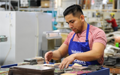 Volunteer at ReStore sorting tile and wearing a blue ReStore apron