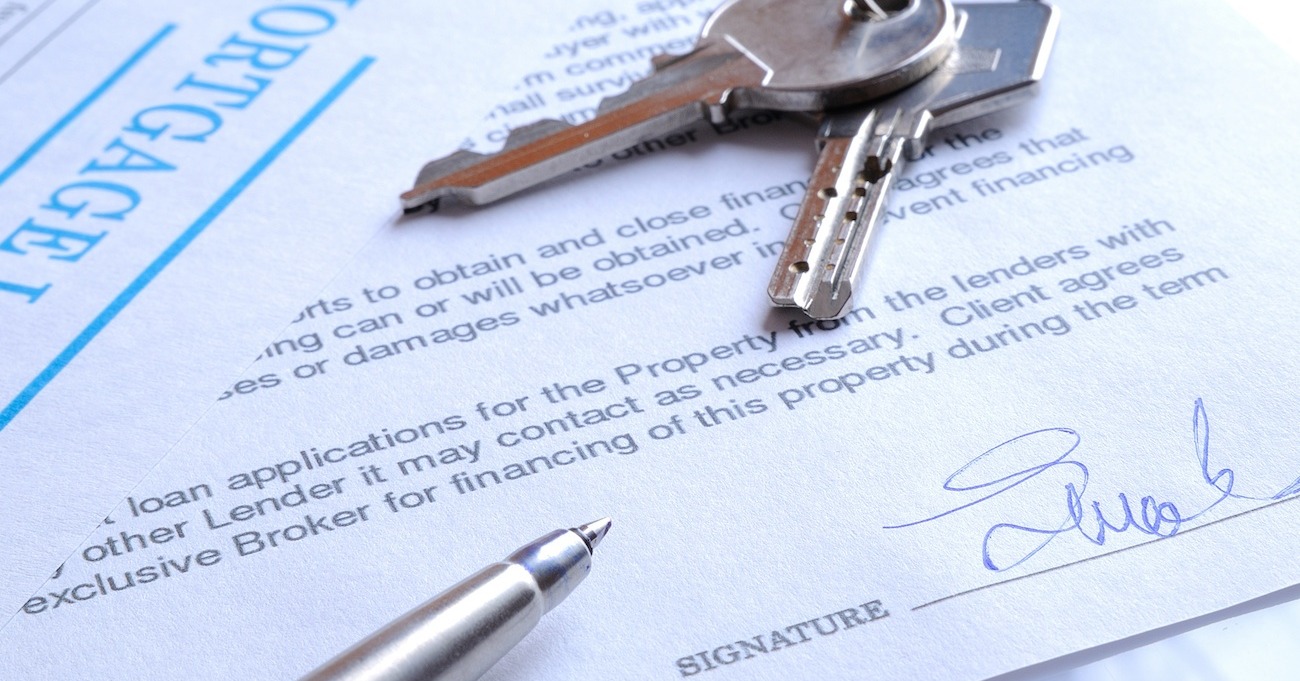 Keys on top of legal paper next to pen