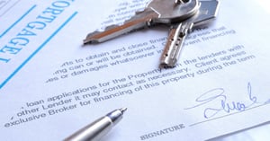 Mortgage documents on a table, with keys and a pen sitting on top.