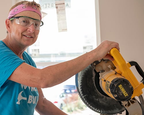 A person in a pink bandana using a saw.