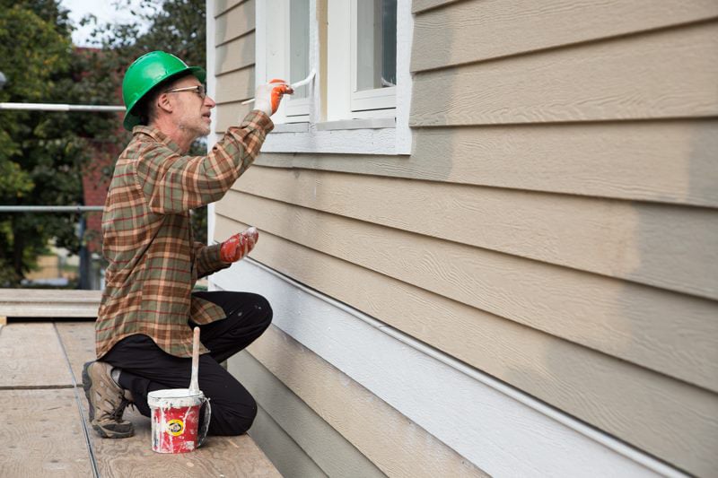 A volunteer painting the trim on windows.