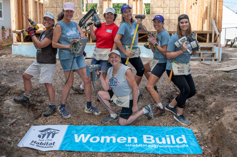 Women Build volunteers posing with power tools.